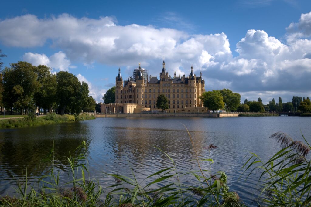 Pałac Schwerin nad spokojnym jeziorem pod dramatycznym niebem